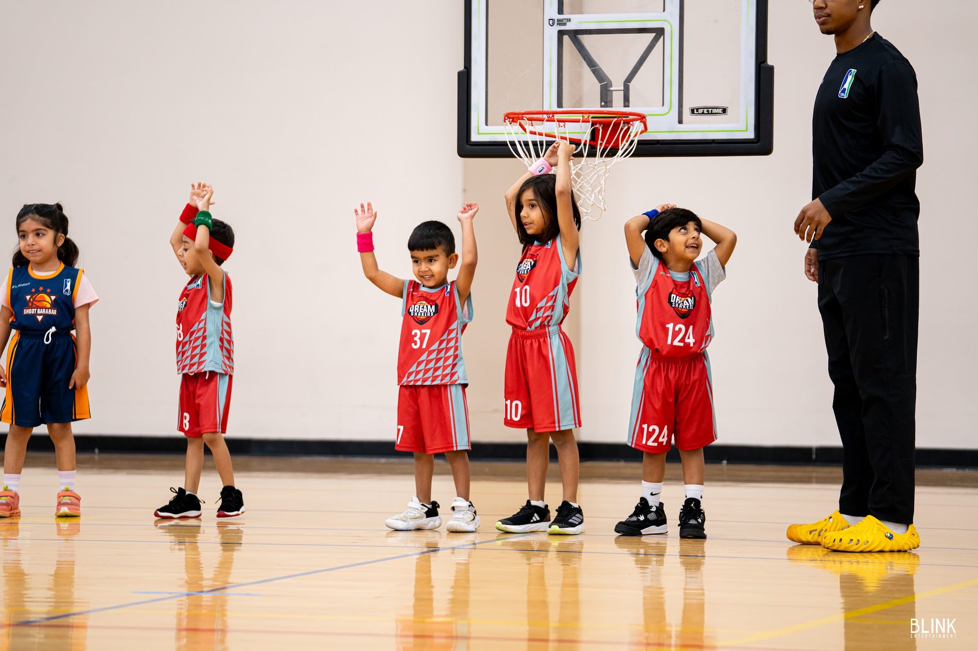 Younger kids gather under a lowered hoop on a Sunday at the gym