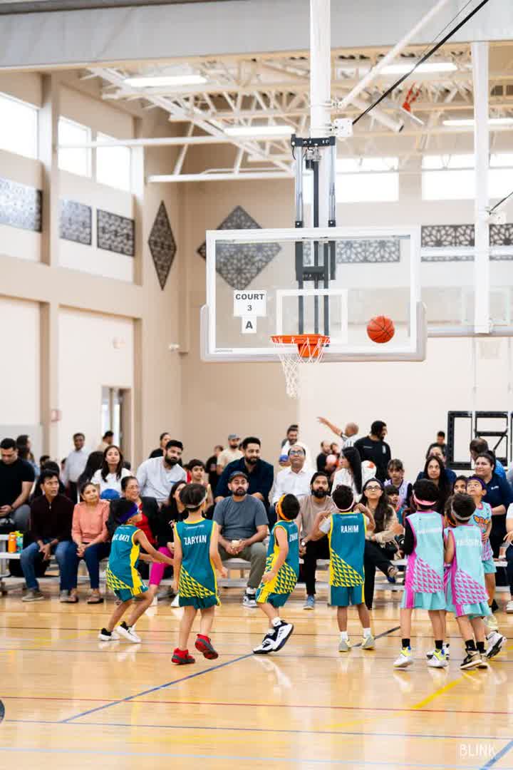 Kids wait under the hoop on Court 3 A with families in the stands