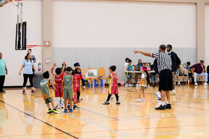 A referee points while a young team listens on the court