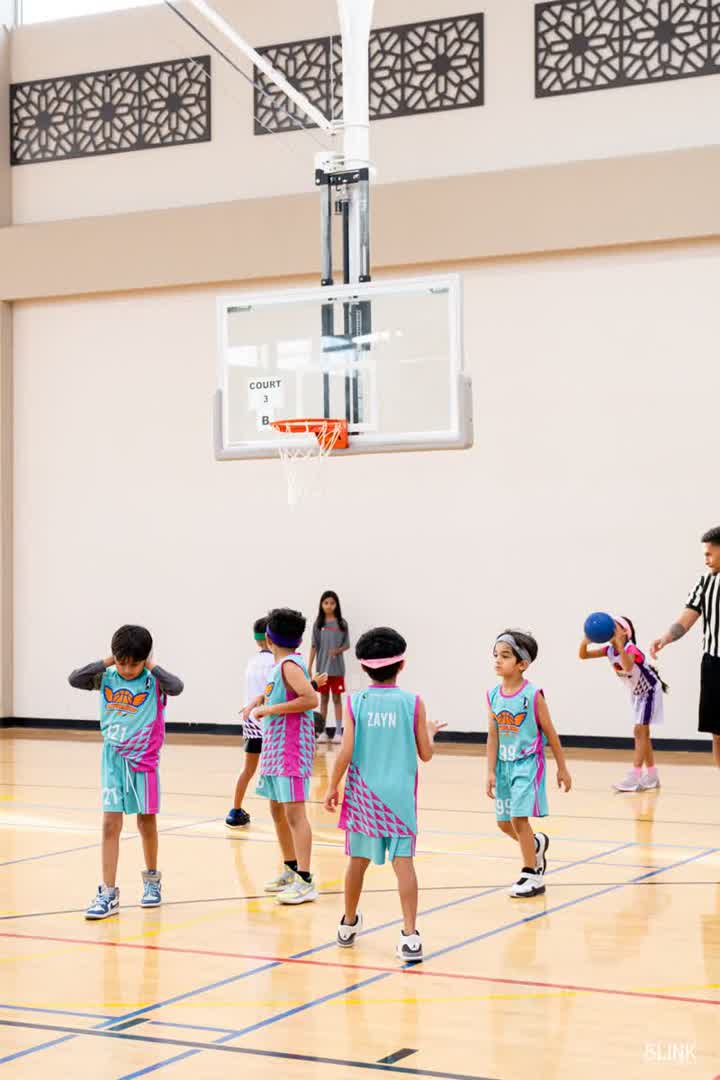 Kids in teal jerseys stand under the hoop on Court 3 B