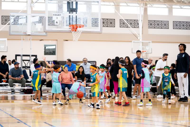 Season 7 players gather on the floor with families along the baseline